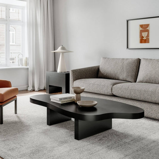 Modern minimalist living room with gray sofa, black coffee table, white lamp, and abstract orange wall art
