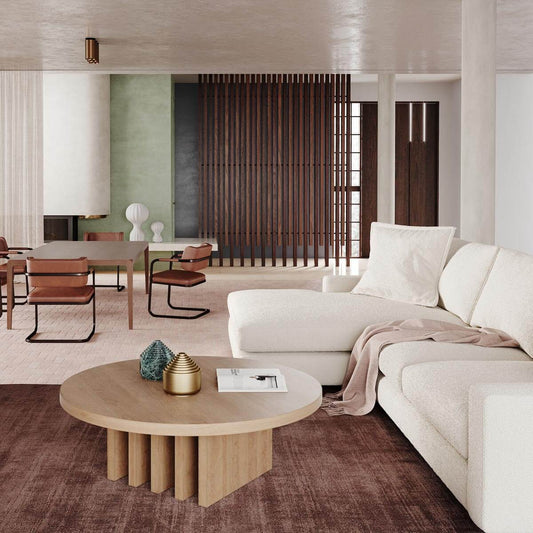 Modern living room with white sectional, round oak coffee table, brown carpet and wooden slat divider wall