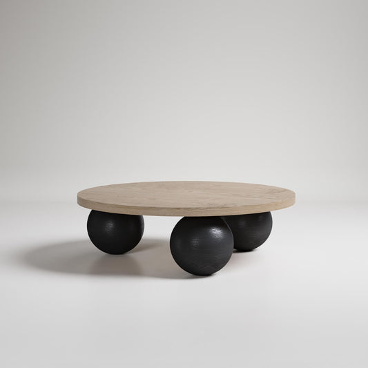 Modern round coffee table with light wood top supported by three large black spherical legs on white background