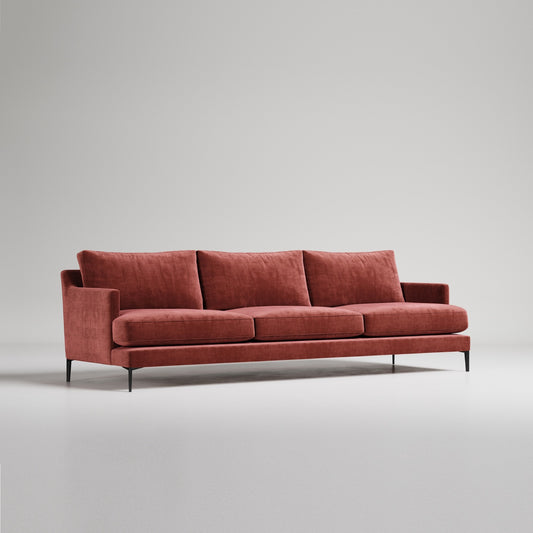 Modern rust-colored velvet sofa with three cushions and slim black metal legs against neutral gray background