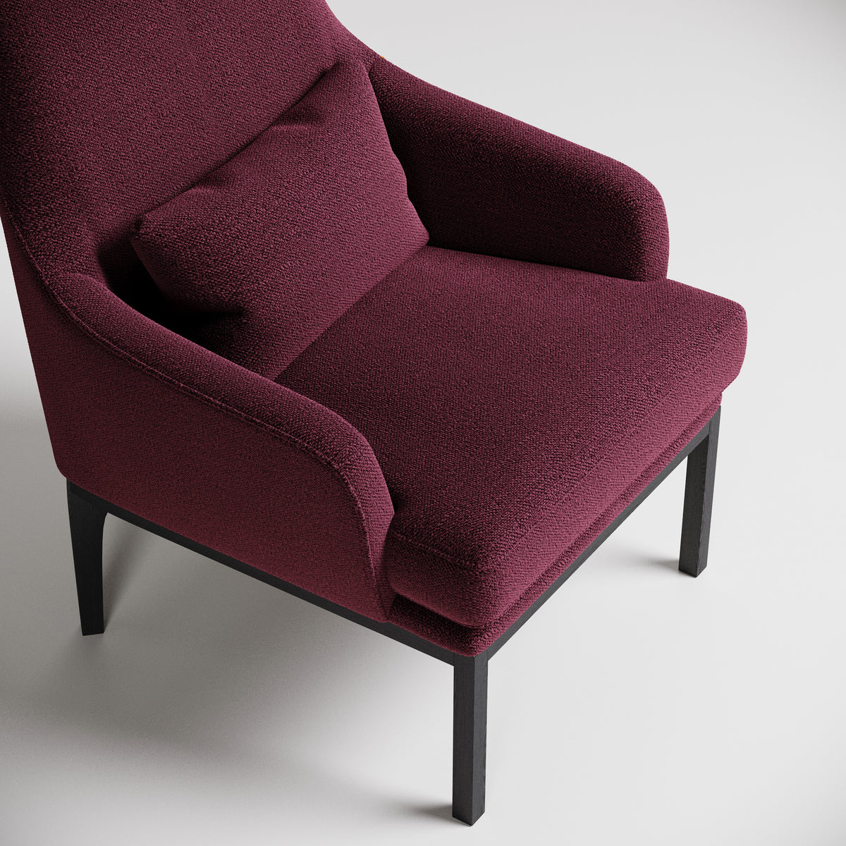 Burgundy upholstered armchair with curved arms and black legs, shown against white background in studio lighting
