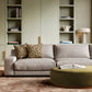 Modern living room with grey sofa, leopard pillows, olive ottoman, built-in shelving and marble table lamp
