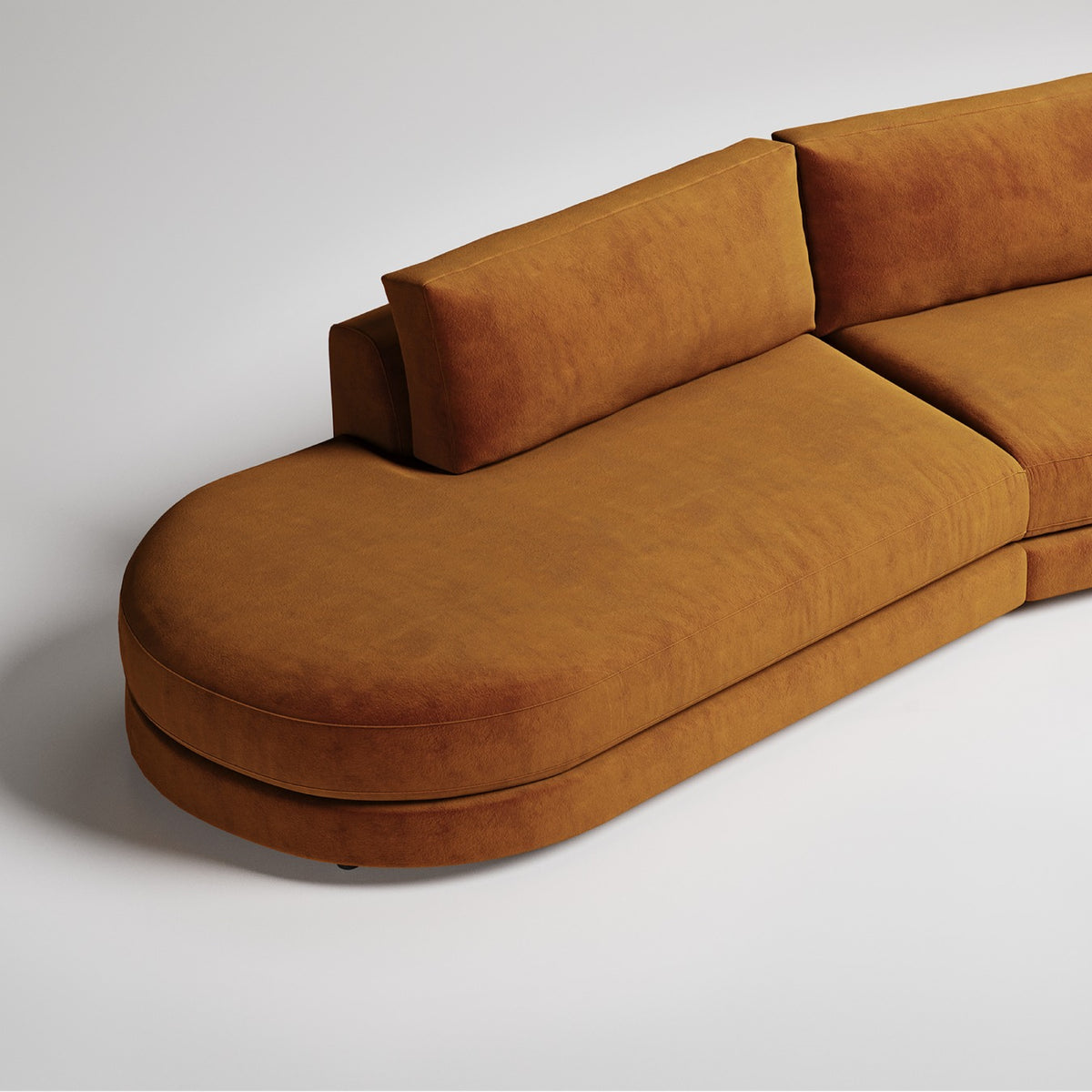 Modern curved sectional sofa in camel brown suede with rounded chaise end, minimalist studio backdrop

