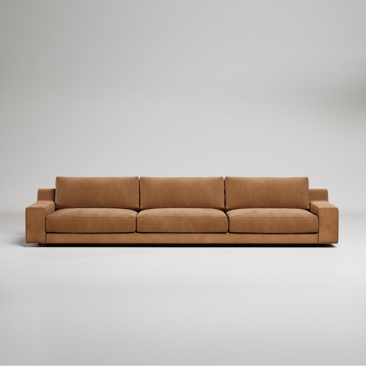Modern extra-long tan leather sofa with clean lines and wide track arms against white background
