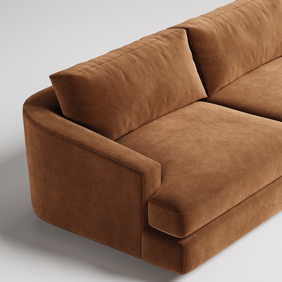 Closeup of modern brown velvet sofa with clean lines and plush cushions against neutral background
