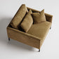 Modern tan velvet armchair with high back and throw pillows on black metal legs, viewed from above

