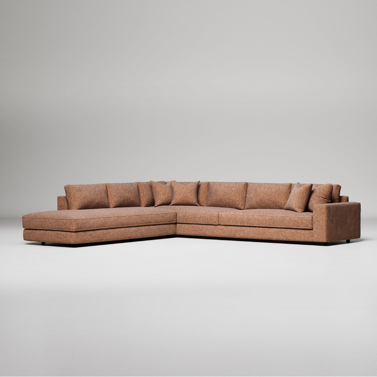 Modern L-shaped sectional sofa in brown textured fabric with chaise lounge and decorative pillows against gray background
