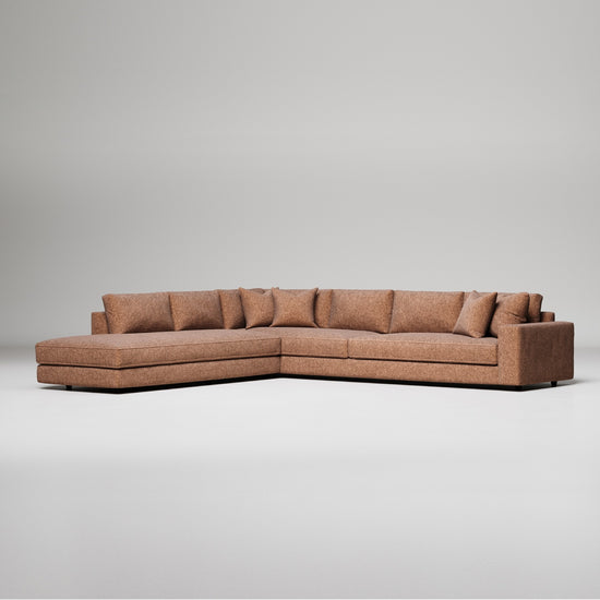 Modern L-shaped sectional sofa in brown textured fabric with chaise lounge and decorative pillows against gray background
