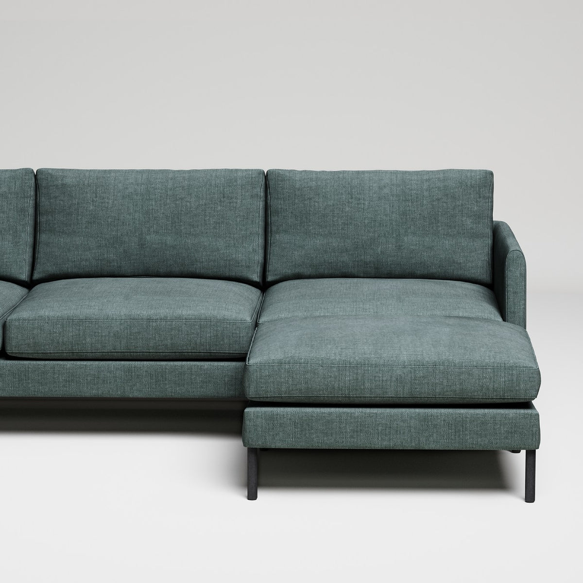 Modern L-shaped sectional sofa in sage green textured fabric with black metal legs against white background
