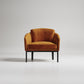 Modern rust-colored velvet armchair with black metal legs against white background, minimalist studio shot
