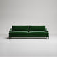 Modern emerald green velvet sofa with black metal legs on white background, studio product shot
