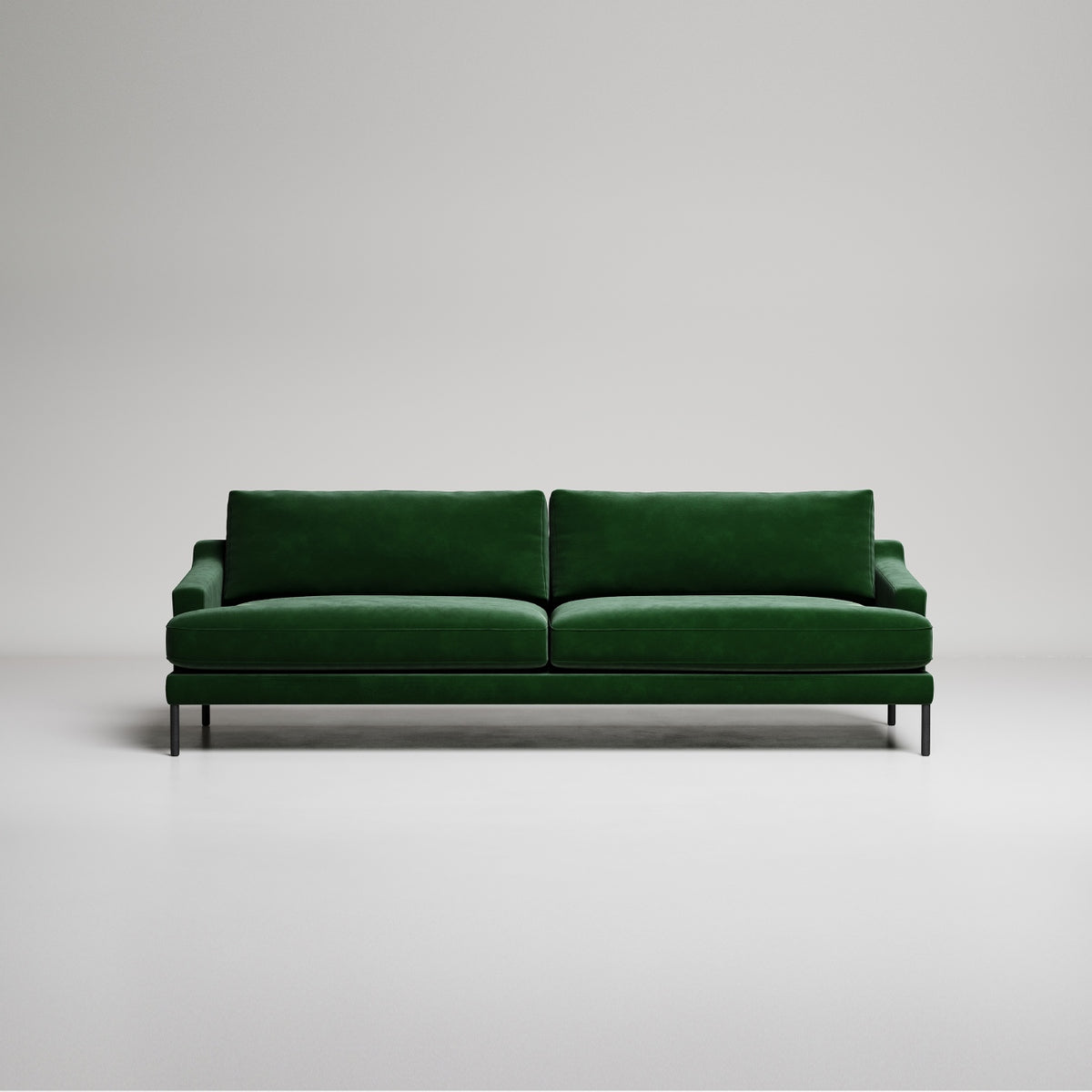 Modern emerald green velvet sofa with black metal legs on white background, studio product shot
