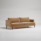 Modern tan velvet sofa with black legs on white background, contemporary minimal design studio photo
