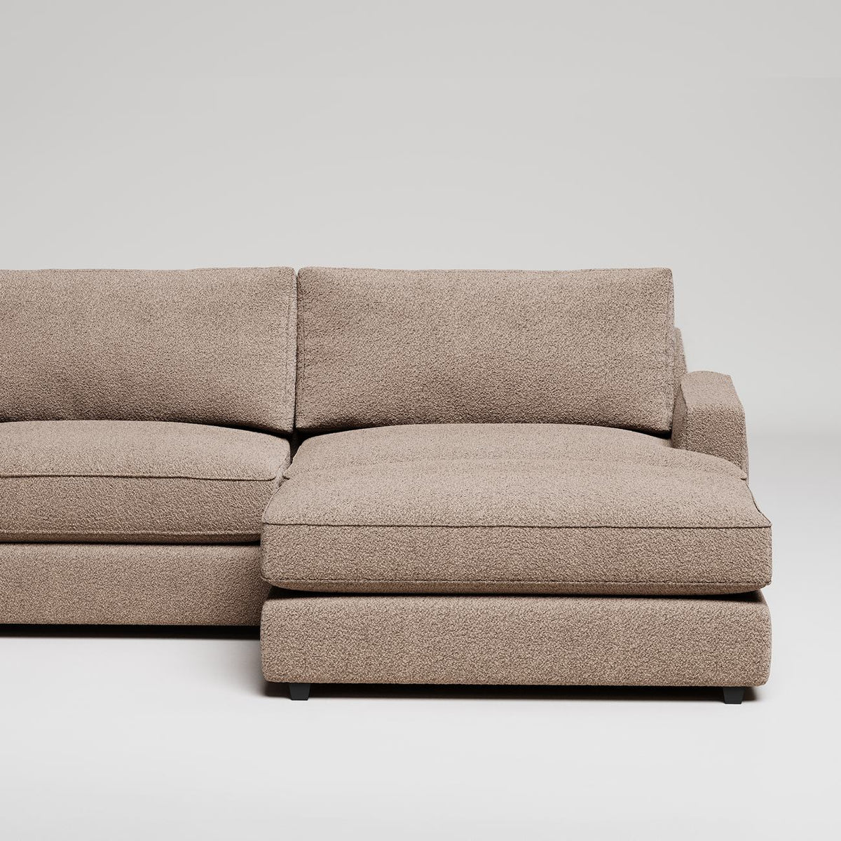 Modern L-shaped sectional sofa in beige textured fabric against white background, minimalist design
