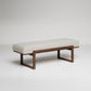 Minimalist upholstered bench with wooden frame featuring textured white fabric and dark walnut-finished legs
