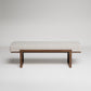 Modern upholstered bench with white houndstooth fabric cushion on minimalist dark wood frame against grey background
