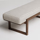Modern upholstered bench with textured cream fabric and dark wooden geometric base against white background
