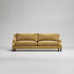 Modern gold velvet sofa with dark wooden legs on light gray background, studio product photo
