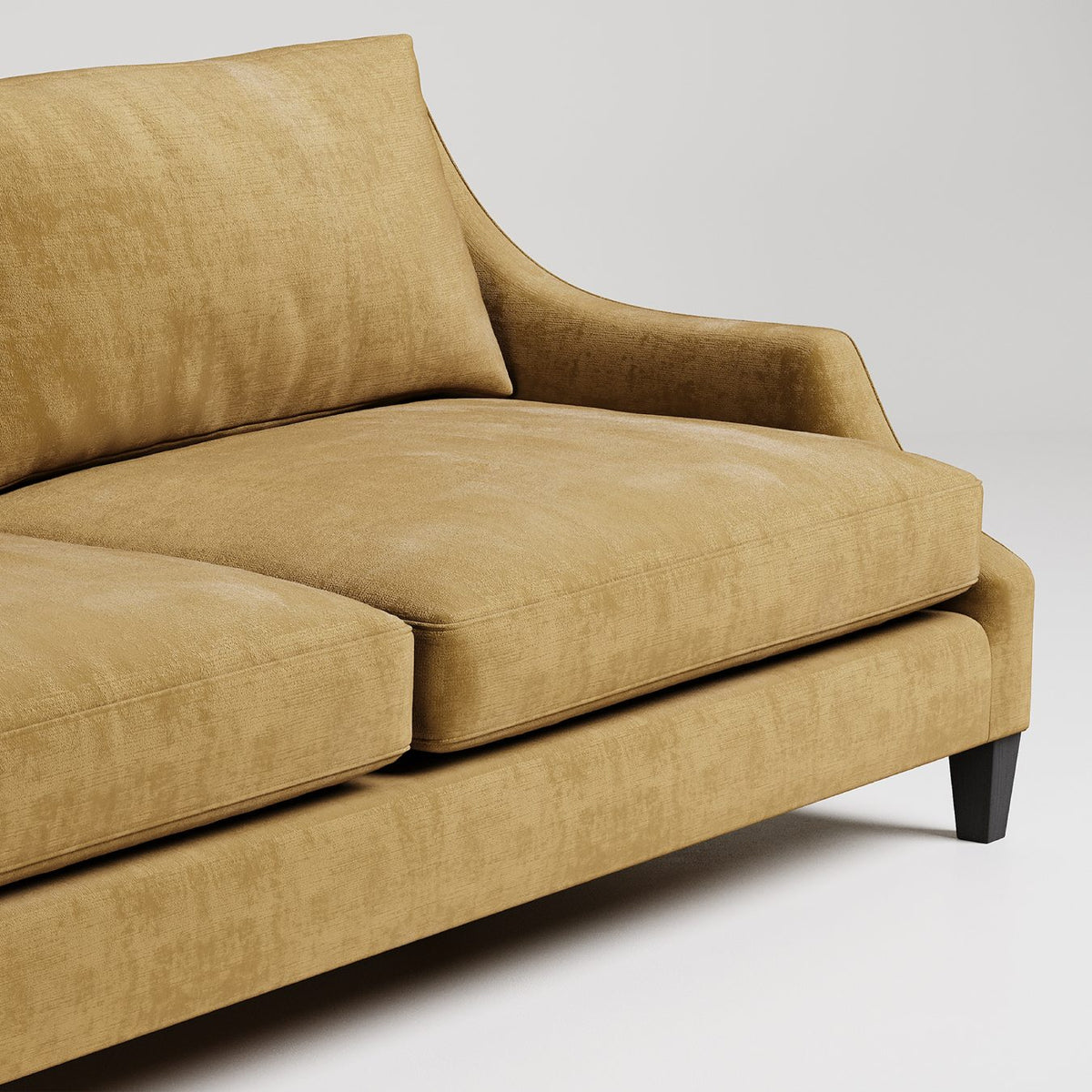 Closeup of modern tan velvet sofa with tapered black legs against white background, showing plush cushions

