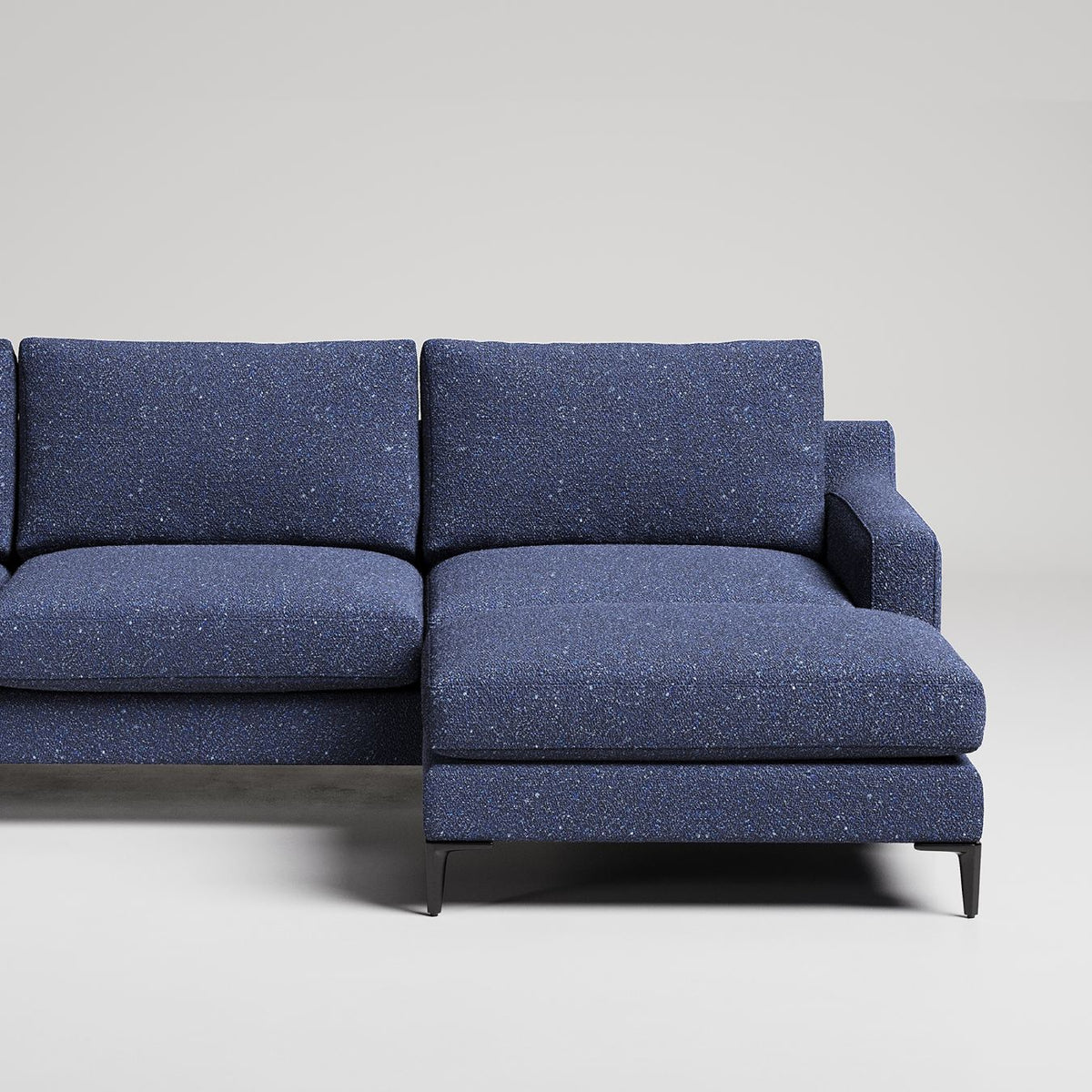 Modern L-shaped sectional sofa in speckled navy blue fabric with slim metal legs against white background

