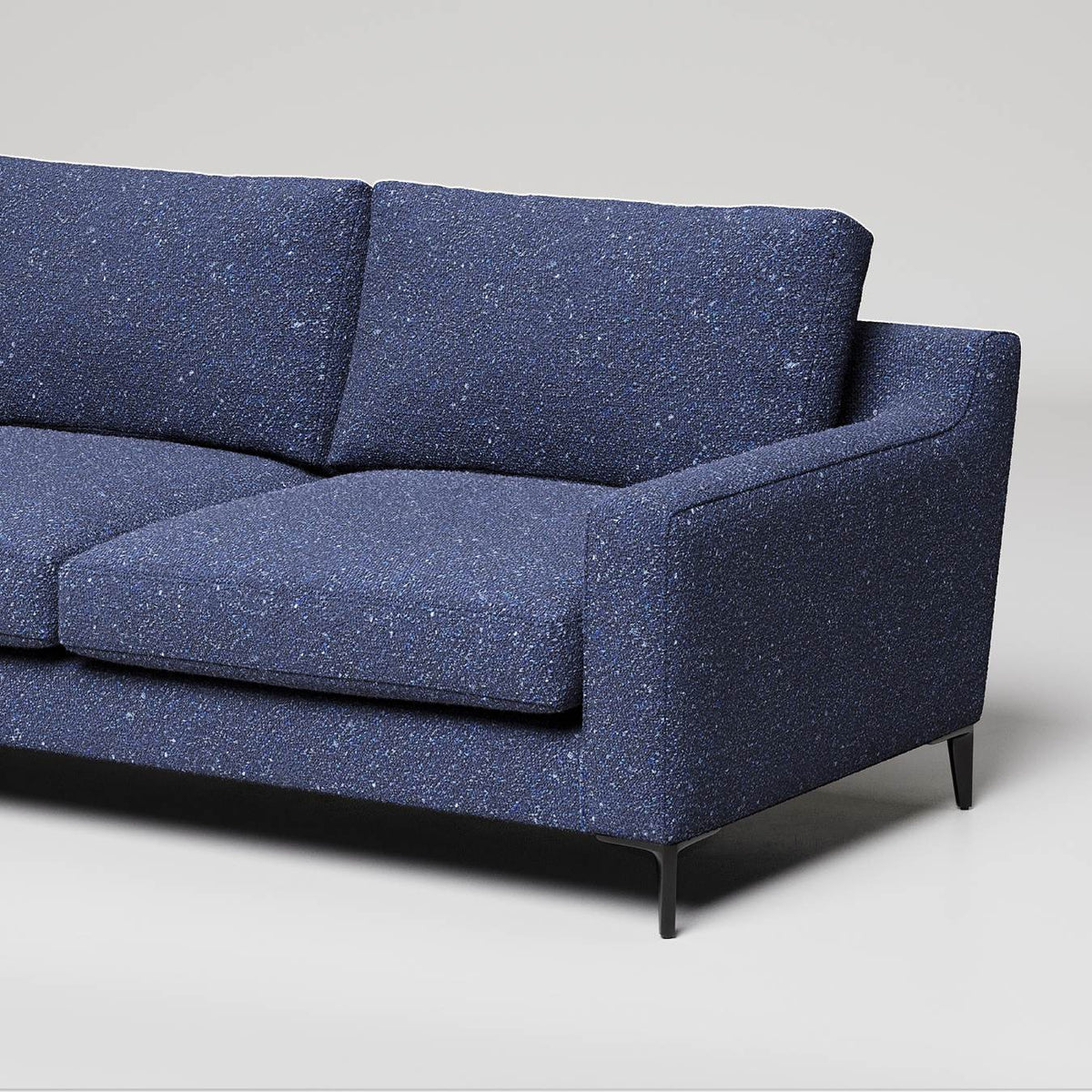 Modern navy blue sofa with speckled fabric texture and slim black metal legs against white background
