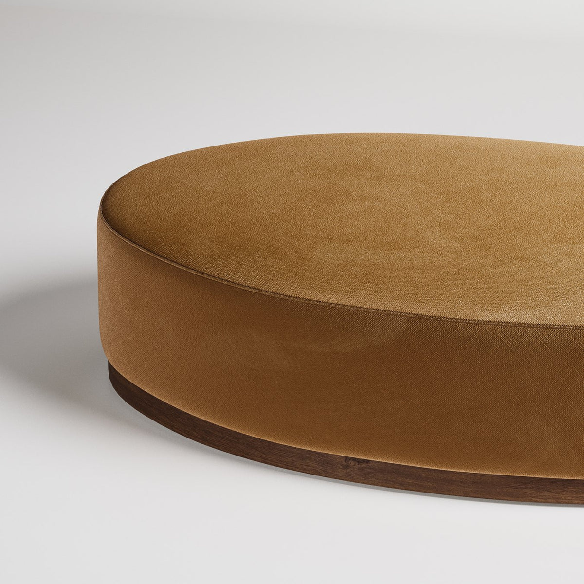 Round velvet ottoman with caramel upholstery and dark wood base, shown in closeup detail against white background
