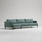 Modern sage green sectional sofa with clean lines, tapered legs, and loose back cushions on light gray background
