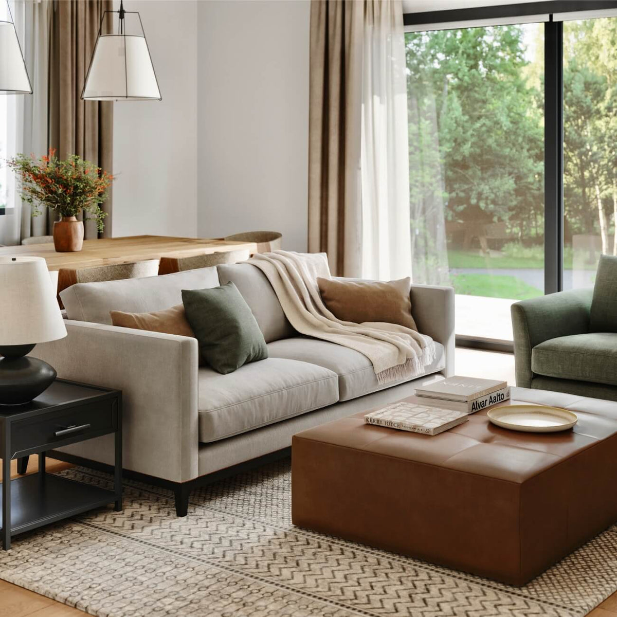 Modern living room with beige sofa, leather ottoman, green accents, natural light, dining area and geometric rug
