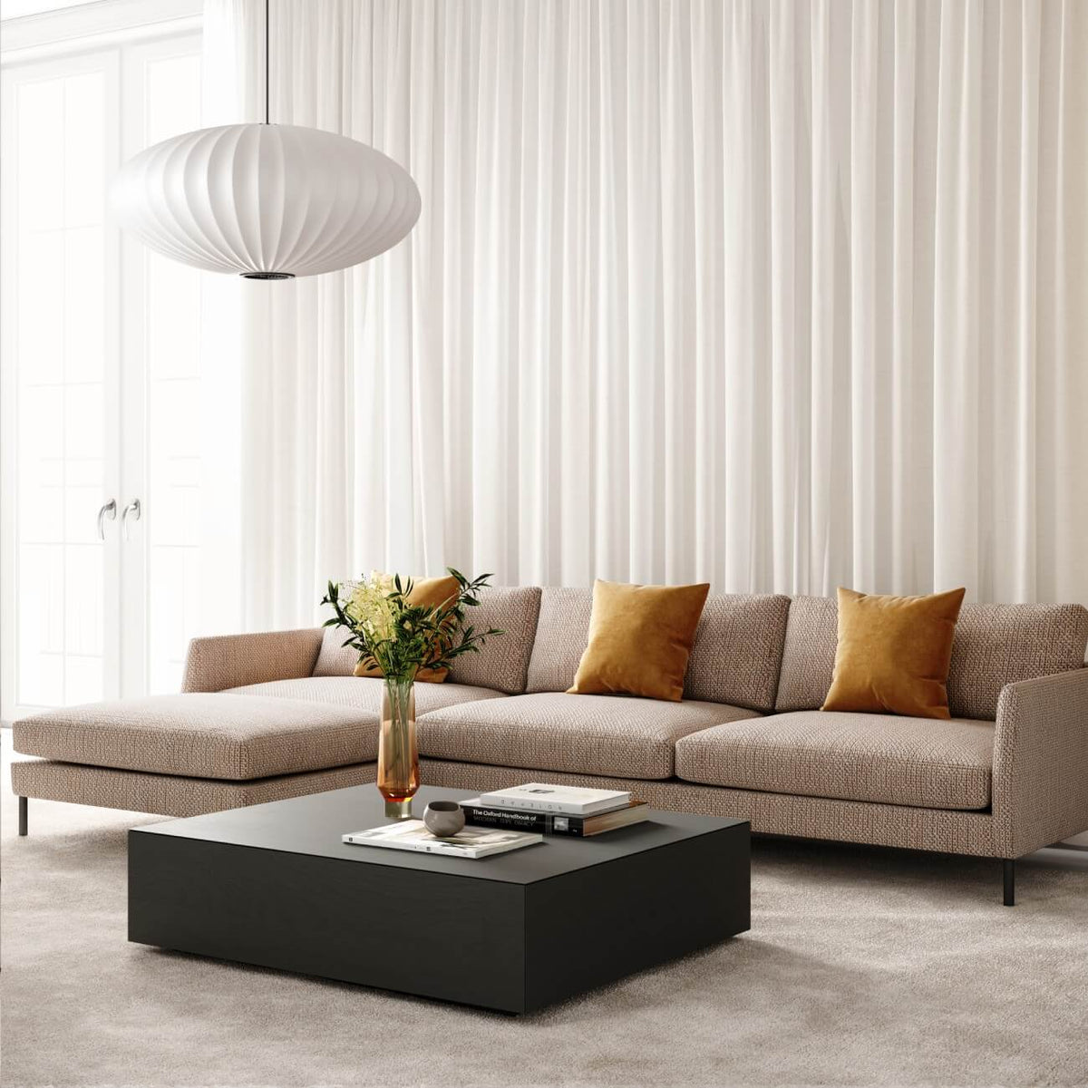Modern living room with beige sectional, gold pillows, black coffee table, white bubble pendant lamp, sheer curtains
