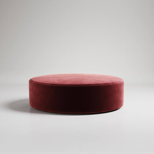 Large round burgundy velvet ottoman or footstool on white background, modern minimalist style

