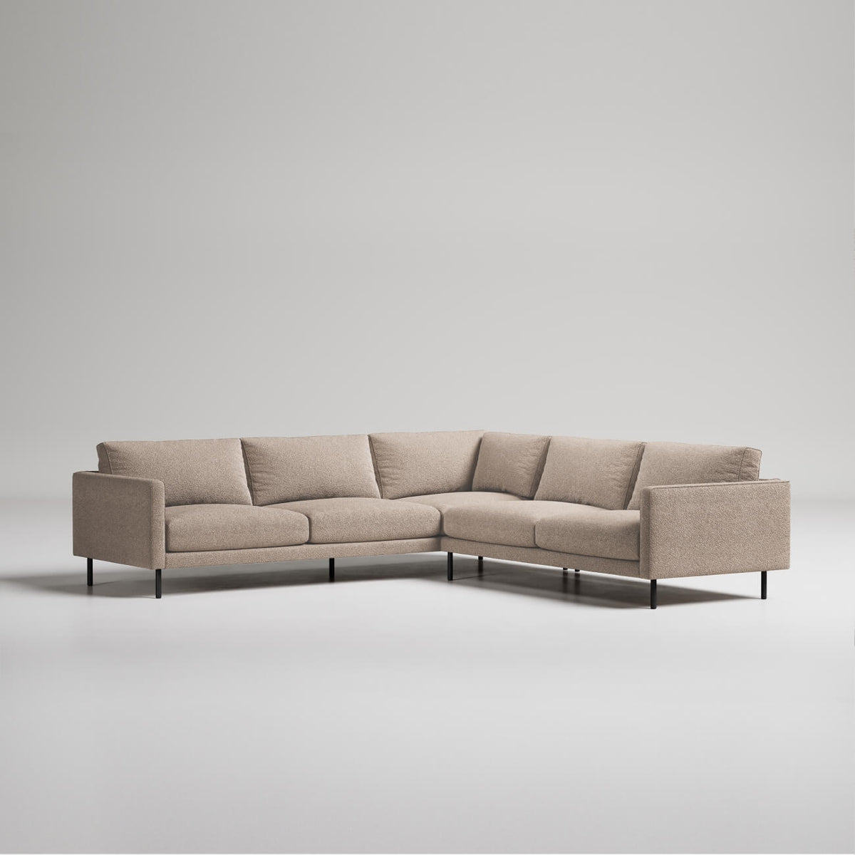 Modern L-shaped beige sectional sofa with slim black metal legs on white background, minimalist contemporary design
