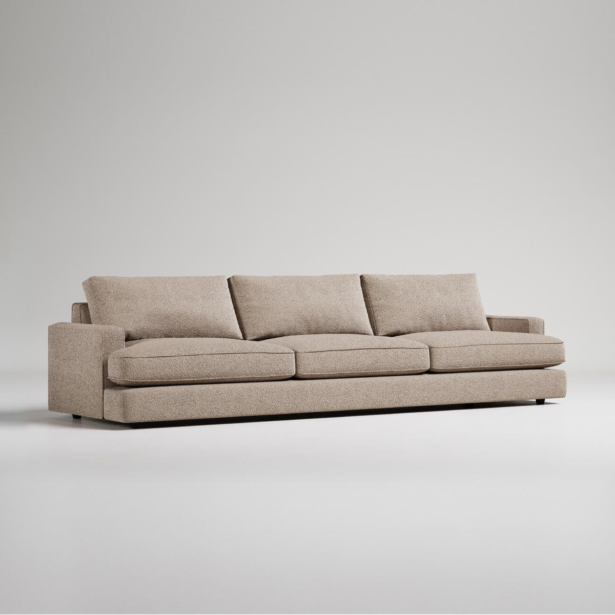 Modern extra-long beige sofa with three cushions and clean lines, photographed against white background
