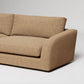Modern beige linen sofa with curved armrest detail against white background, studio product photography
