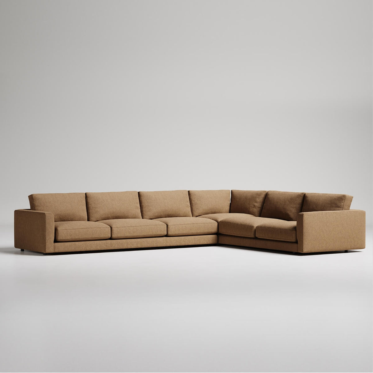 Large L-shaped sectional sofa in tan upholstery with clean modern lines and deep cushions against grey backdrop
