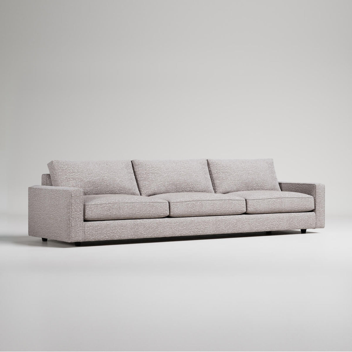 Modern extra-long light gray sofa with clean lines and three cushions against white background
