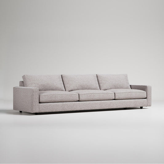 Modern extra-long light gray sofa with clean lines and three cushions against white background
