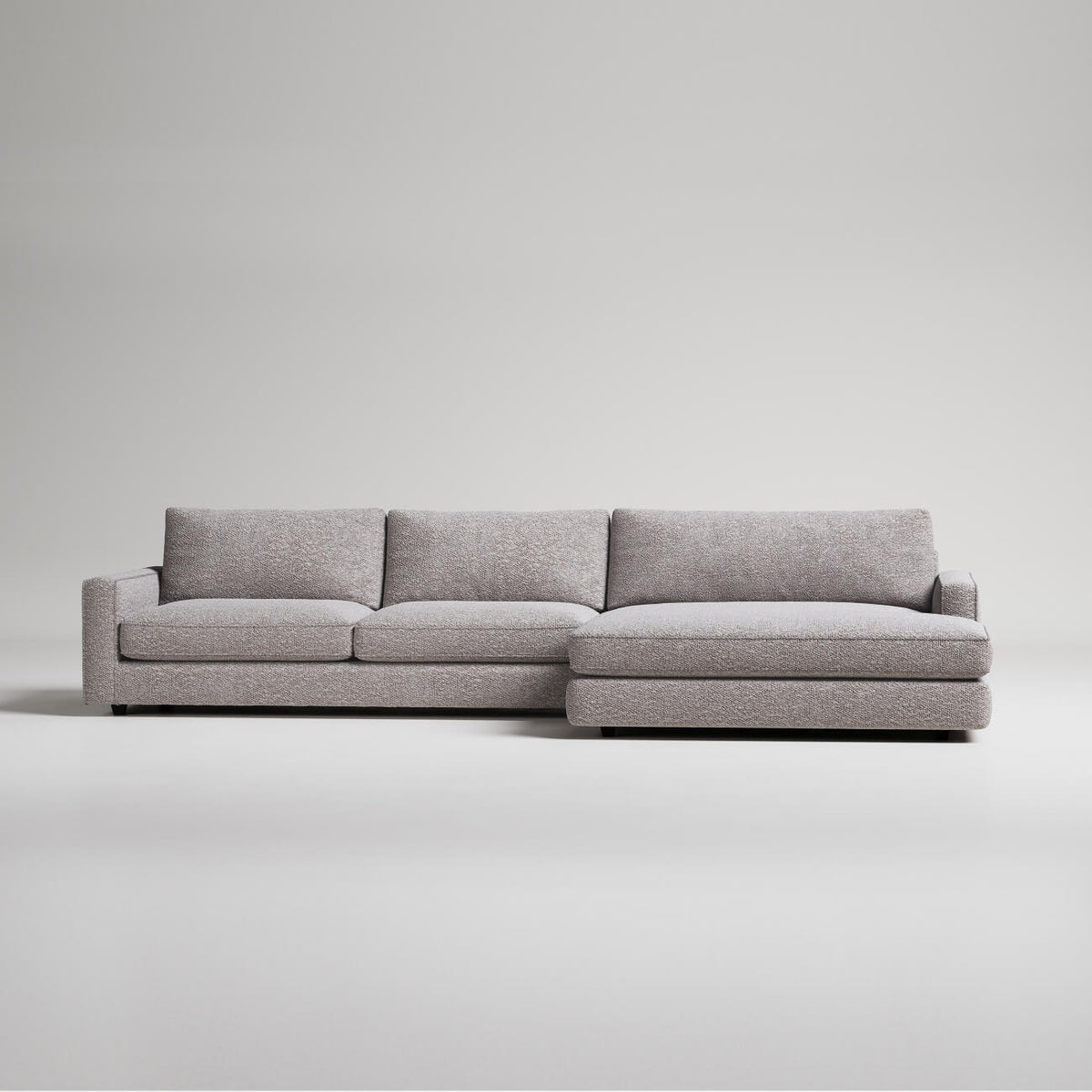 Modern gray L-shaped sectional sofa with textured fabric upholstery on white background, minimalist design
