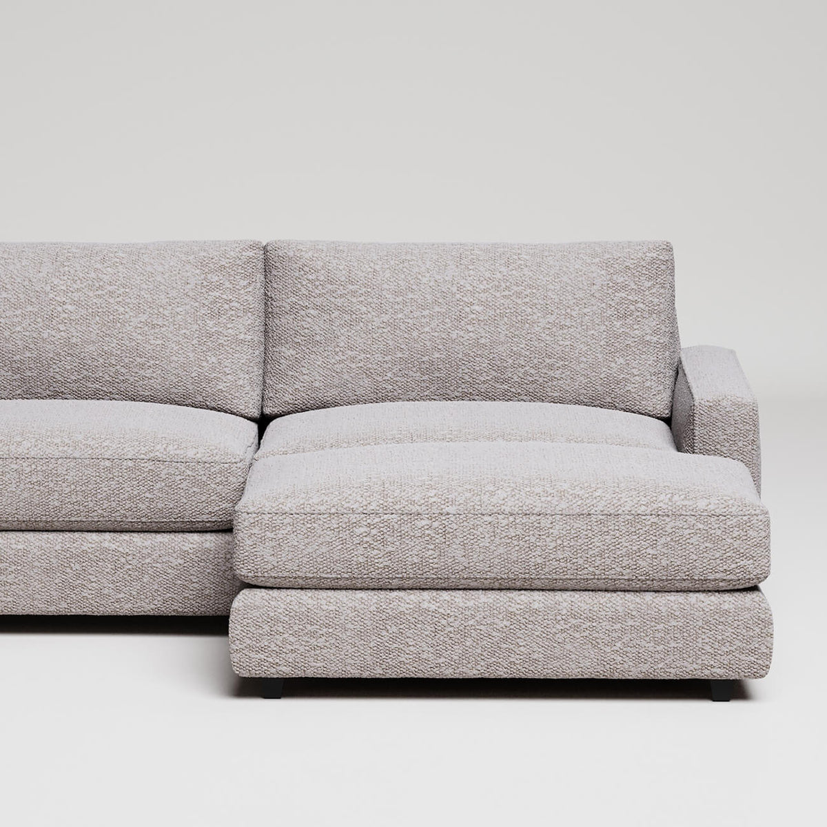 Modern L-shaped sectional sofa in light grey textured fabric against white background
